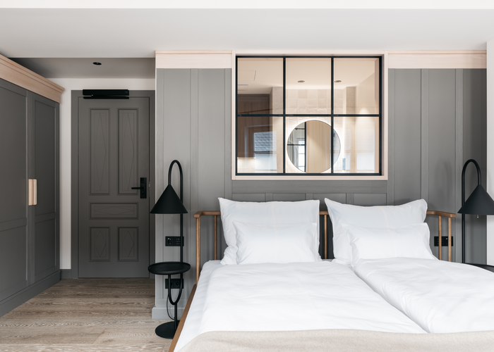 Le porte e i rivestimenti delle pareti verniciati di grigio, insieme ai mobili in legno massello colorato, conferiscono alle camere dei piani superiori un'atmosfera accogliente. | © Refugium Lunz / Gregor Hofbauer